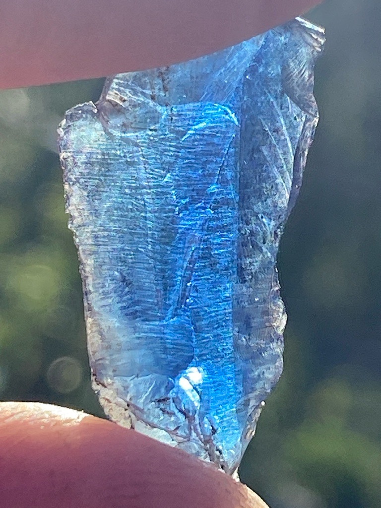 Not a diamond; this specimen exhibits conchoidal fracture lines and blue chatoyancy or iridescence characteristic of a raw mineral or synthetic glass/quartz rather than diamond. - Uncut raw rough crystal fragment with irregular morphology