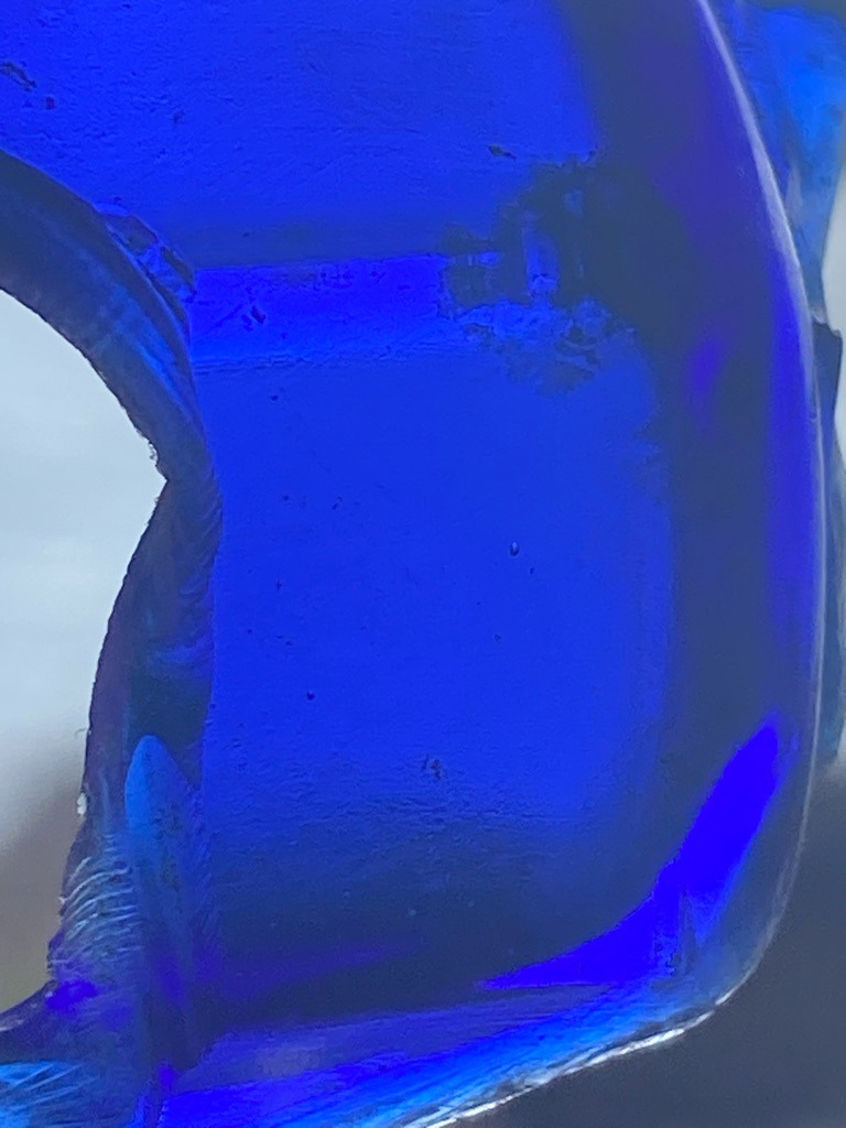 Not a diamond; this image displays intensely blue-tinted glass or a synthetic blue material, lacking the optical and structural properties of a genuine diamond. - Irregular fragment or abstract blue glass piece, not a standard faceted gemstone shape.