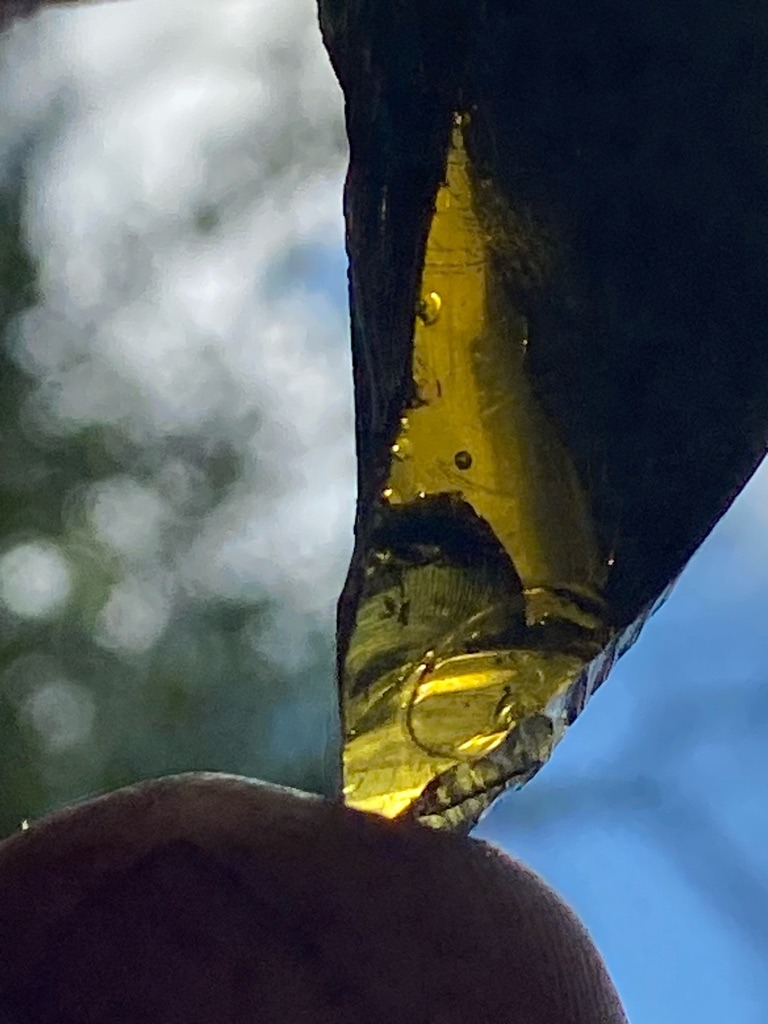 Not a diamond; this is a piece of colored glass containing characteristic round gas bubbles. - Irregular raw fragment / shard
