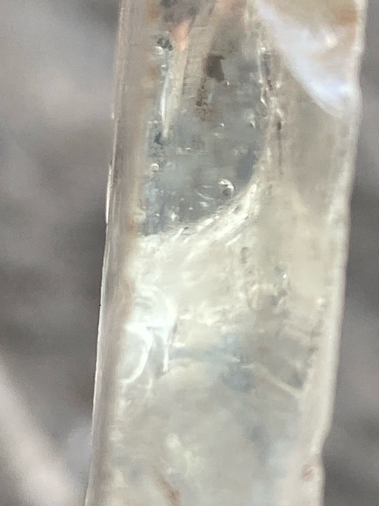 Not a diamond; this image shows a natural ice formation or icicle, displaying characteristic trapped air bubbles and elongated crystalline structure typical of frozen water. - Irregular elongated form, characteristic of a natural icicle.