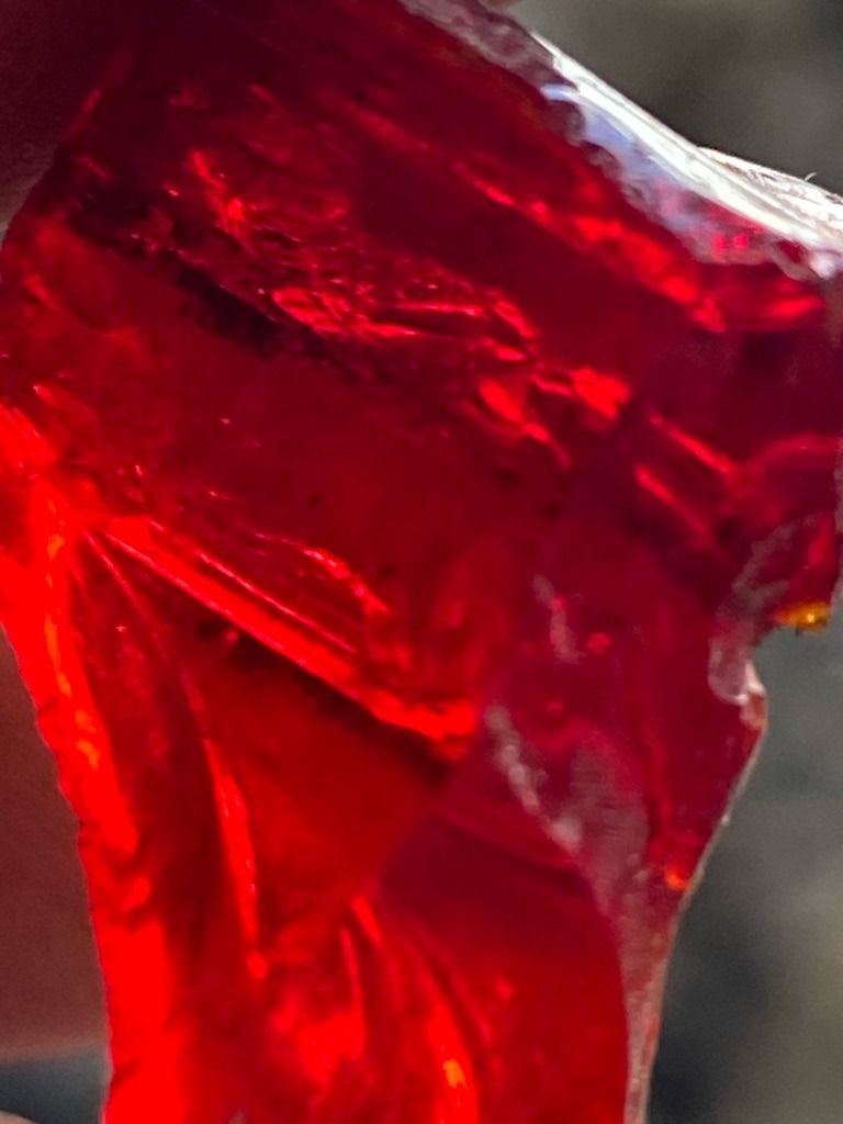 Not a diamond; this specimen appears to be red glass, synthetic spinel, or colored resin due to the conchoidal fracture and lack of diamond crystal structure. - Raw, uncut, amorphous fragment / unpolished chunk