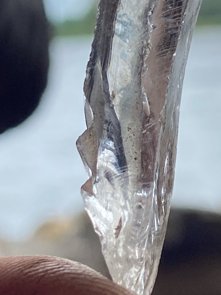 The specimen shown is not a diamond; it appears to be a natural mineral crystal fragment, likely quartz or a similar transparent crystalline mineral, rather than a genuine diamond. - Rough uncut crystal shard / irregular elongation