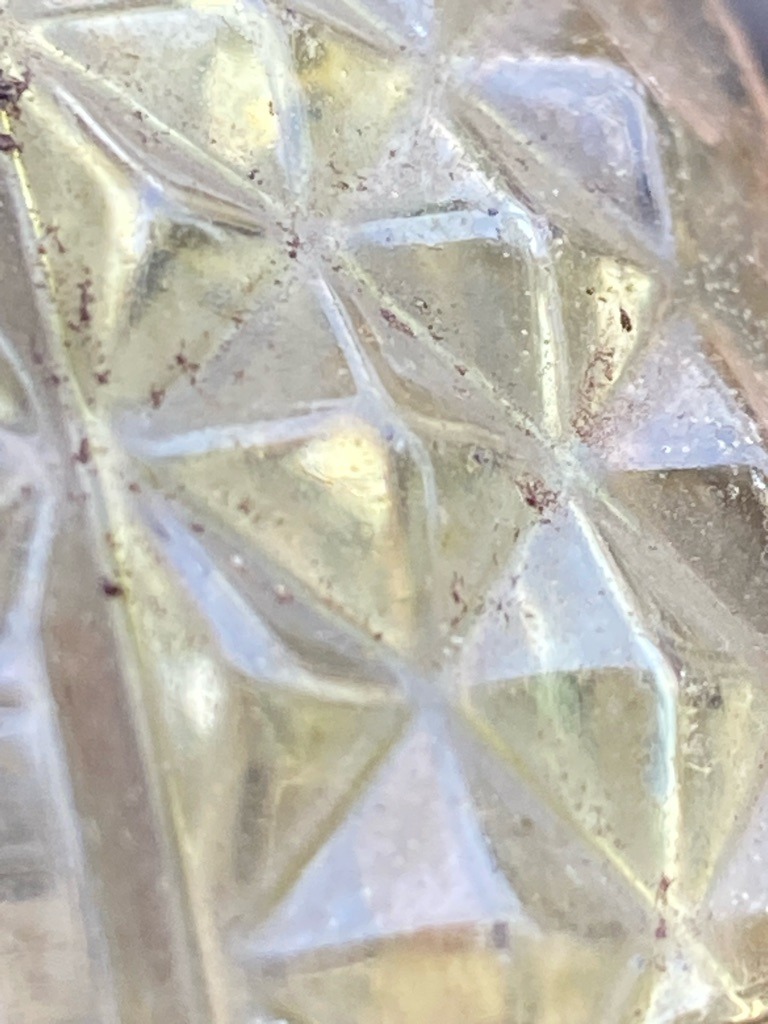 Not a diamond; this appears to be molded or cut glass / crystal tableware with dirt or residue accumulated in the facet junctions. - Multi-faceted geometric glass pattern, non-standard for gemstones.