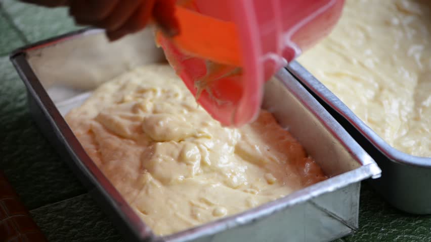pouring dough into rectangular aluminium cake mould