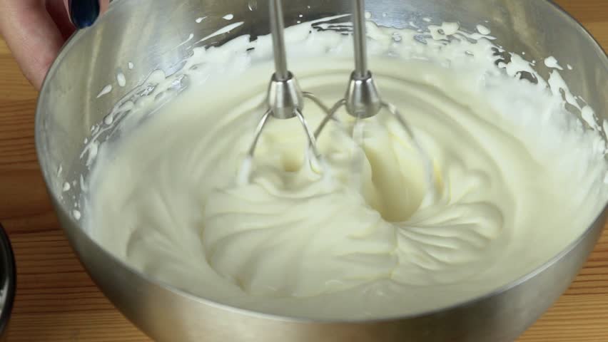 Close up: Whisks whipped egg whites and sugar in the bowl of glass ...