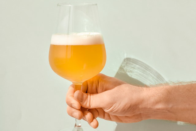 グラスに注がれたビールを持つひと