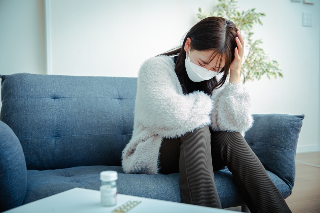 頭をおさえるマスクの女性