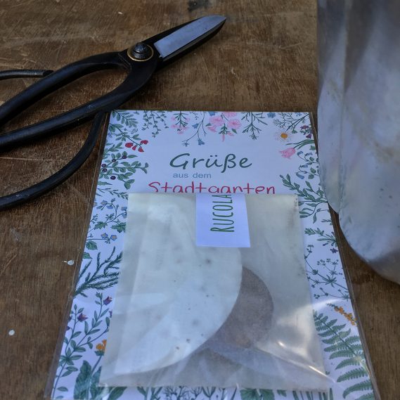 Grüße aus dem Stadtgarten Postkarte zwischen Puddingform und Schere auf Holztisch