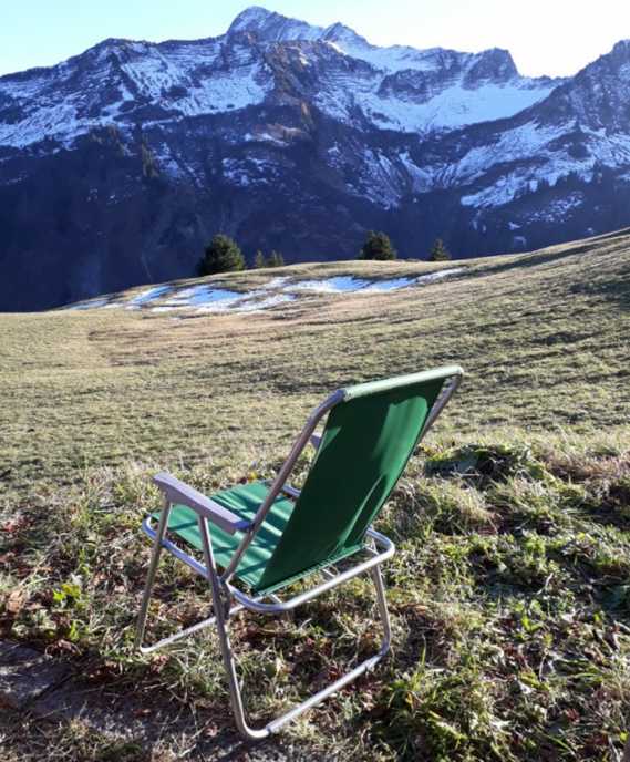 Bergkulisse mit leerem, grünem Klappstuhl, Einladung zum Durchatmen