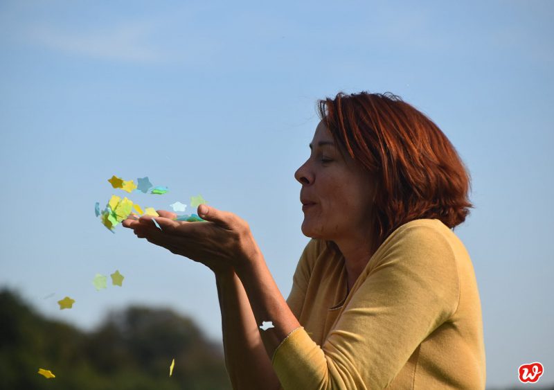 Heike Konfetti in die Luft pustend von der Seite