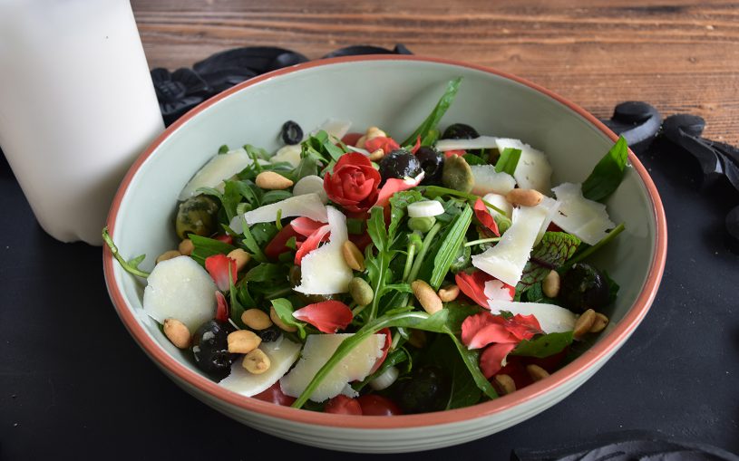 Bunter Salat mit Blumen und Parmesan, Tomaten auf schwarzem Untergrund mit Kerzen