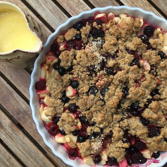 Gebackenes Crumble mit Kanne Vanillesoße auf Holztisch