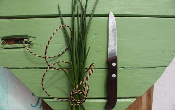 Messer und Schnittlauch auf grünem Holzherz