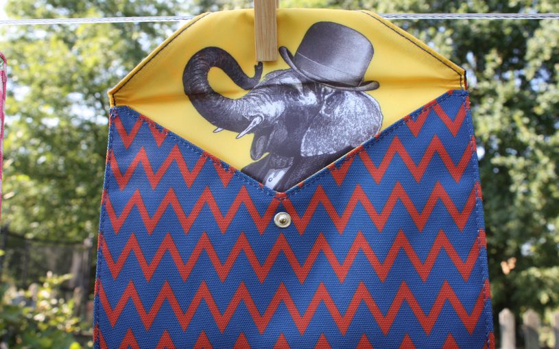 EBook-Tasche rot-blau auf Leine aufgeklappt, Blick auf Elefant mit Melone