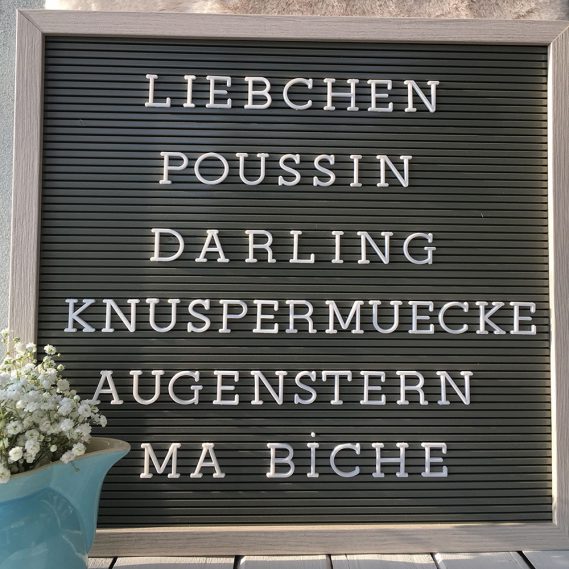 Graues Letterboard mit weißen Kosenamen und Kännchen mit Schleierkraut, verliebt, Liebe, Valentinstag, die kleinen Gesten, unbezahlbar schön