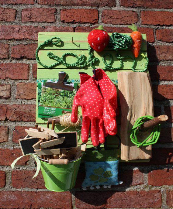 Grünes Gartenutensilo vor roter Mauer, Gartenwerkzeug auf selbstgemachtem Utensilo, DIY-Uensilo