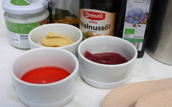 Porzellanschüsseln mit Senf, Marmelade, Sirup vor verschiedenen Ölen