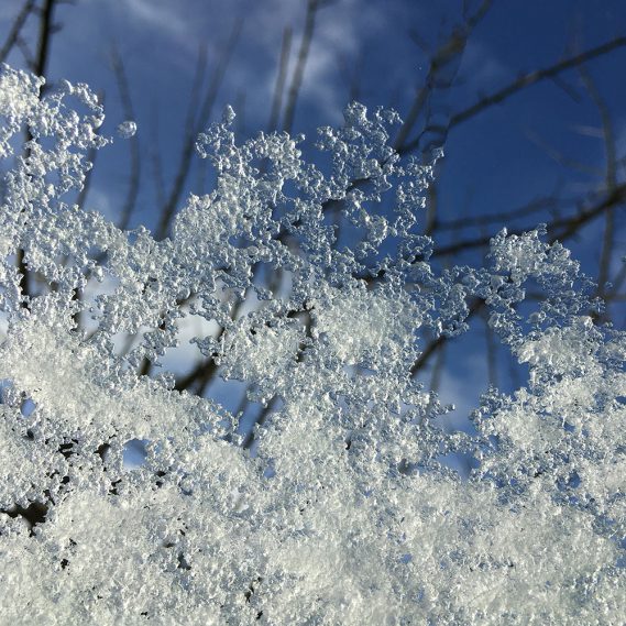 Blick aus dem Fenster, Eis-Schneeschicht auf Fenster, Wintereindruck, blauer Himmel, schöner Tag