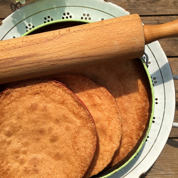 3gebackene Kuchenböden mit Holzrolle auf weißem Durchschlag