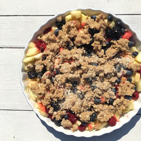 Apfel-Beeren-Crumble in Form auf weißem Untergrund ungebacken