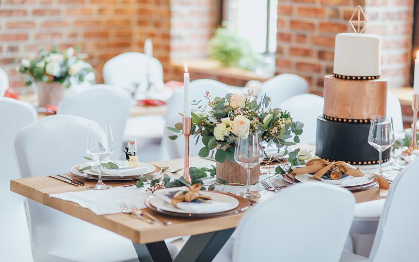 Hochzeitstische gedeckt in Kupferoptik mit Sträußen und dreistöckiger Torte