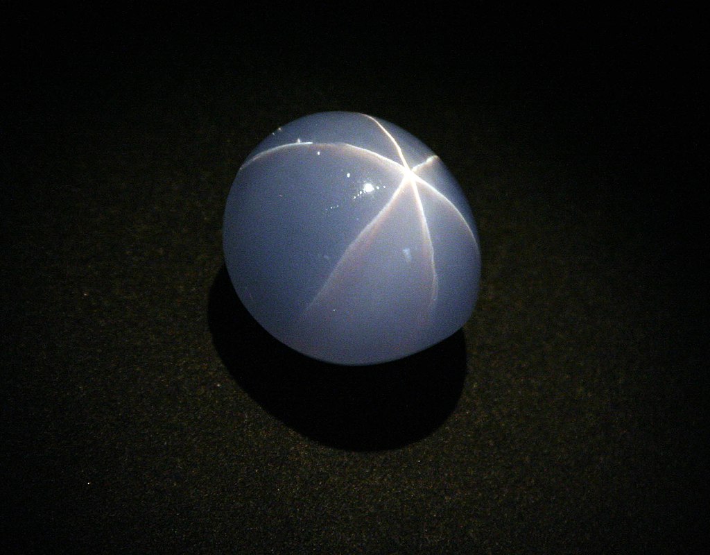 blue cabochon star sapphire against a black background