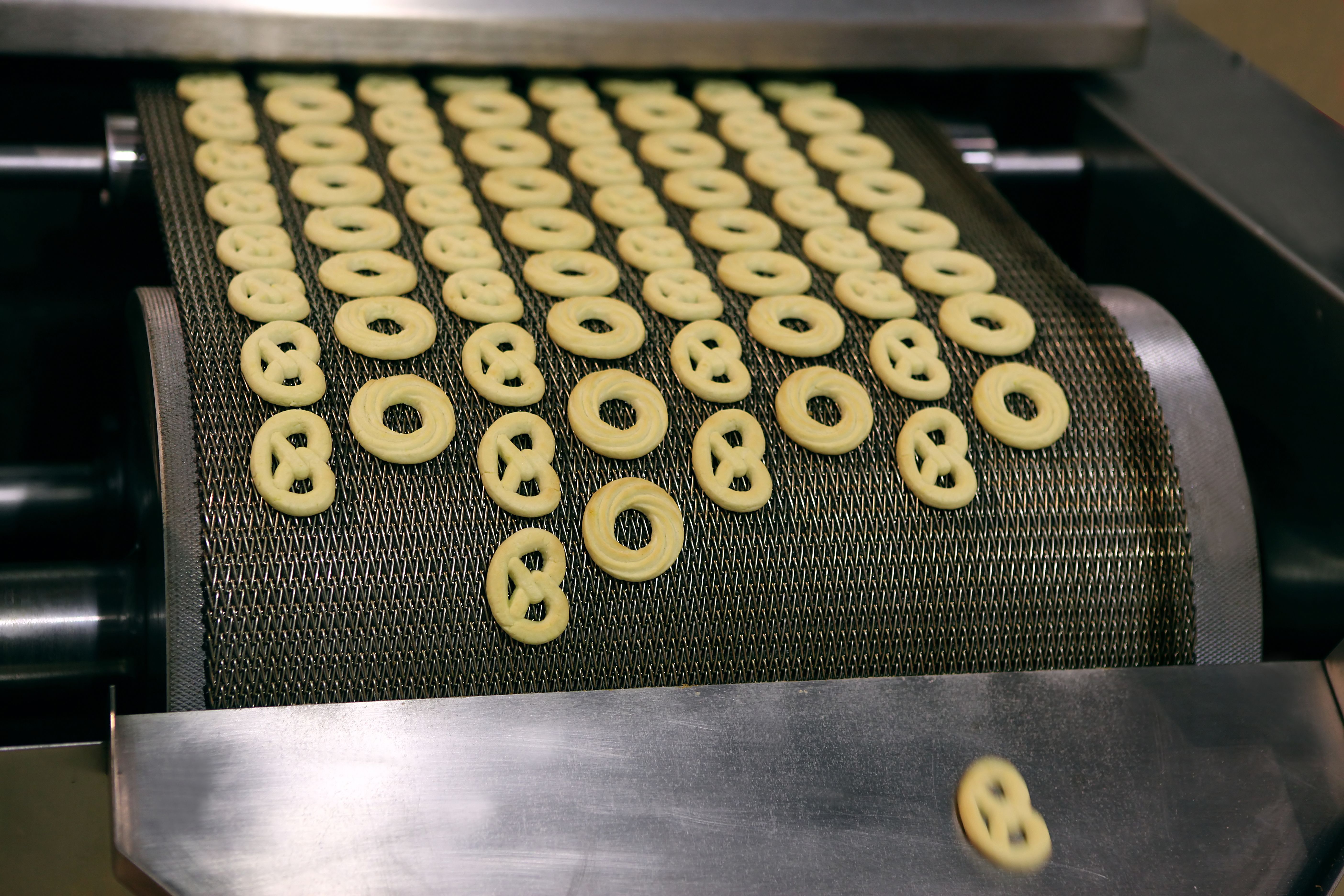 La imagen muestra la producción de galletas en una cinta transportadora.