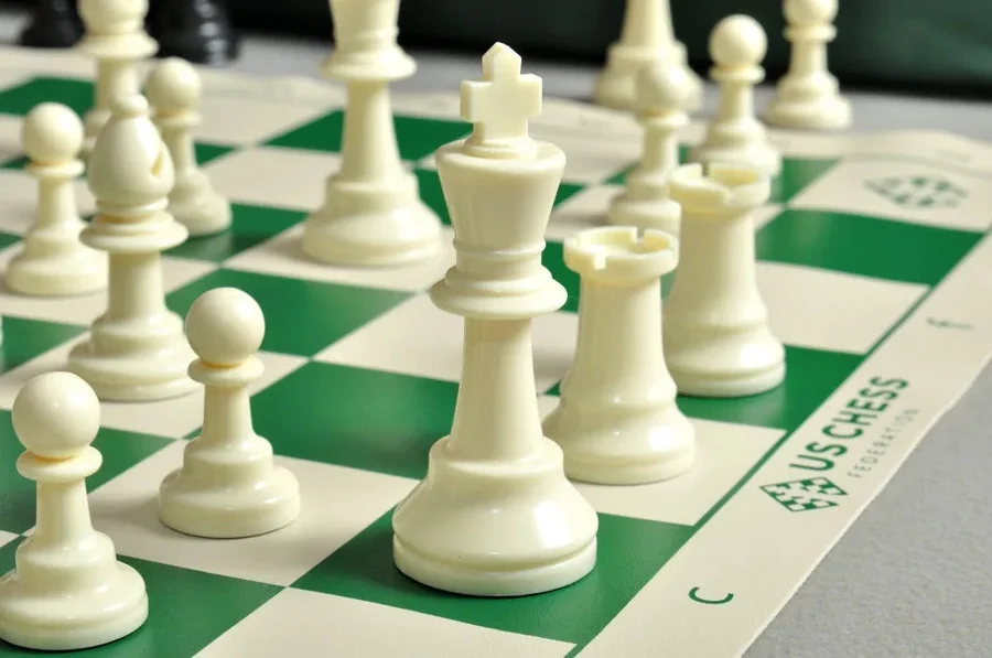 Plastic chess pieces on a vinyl board with the king centralized.