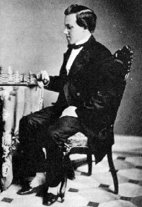 Paul Morphy at age 21 in a black and white photo sitting at a chessboard to play
