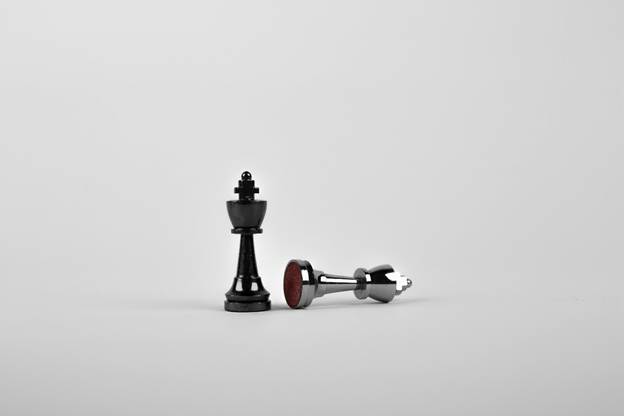 A black king standing on a white space next to a toppled white king