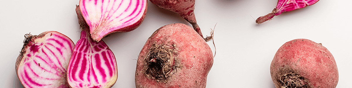 Image of halved and whole beets on a white background