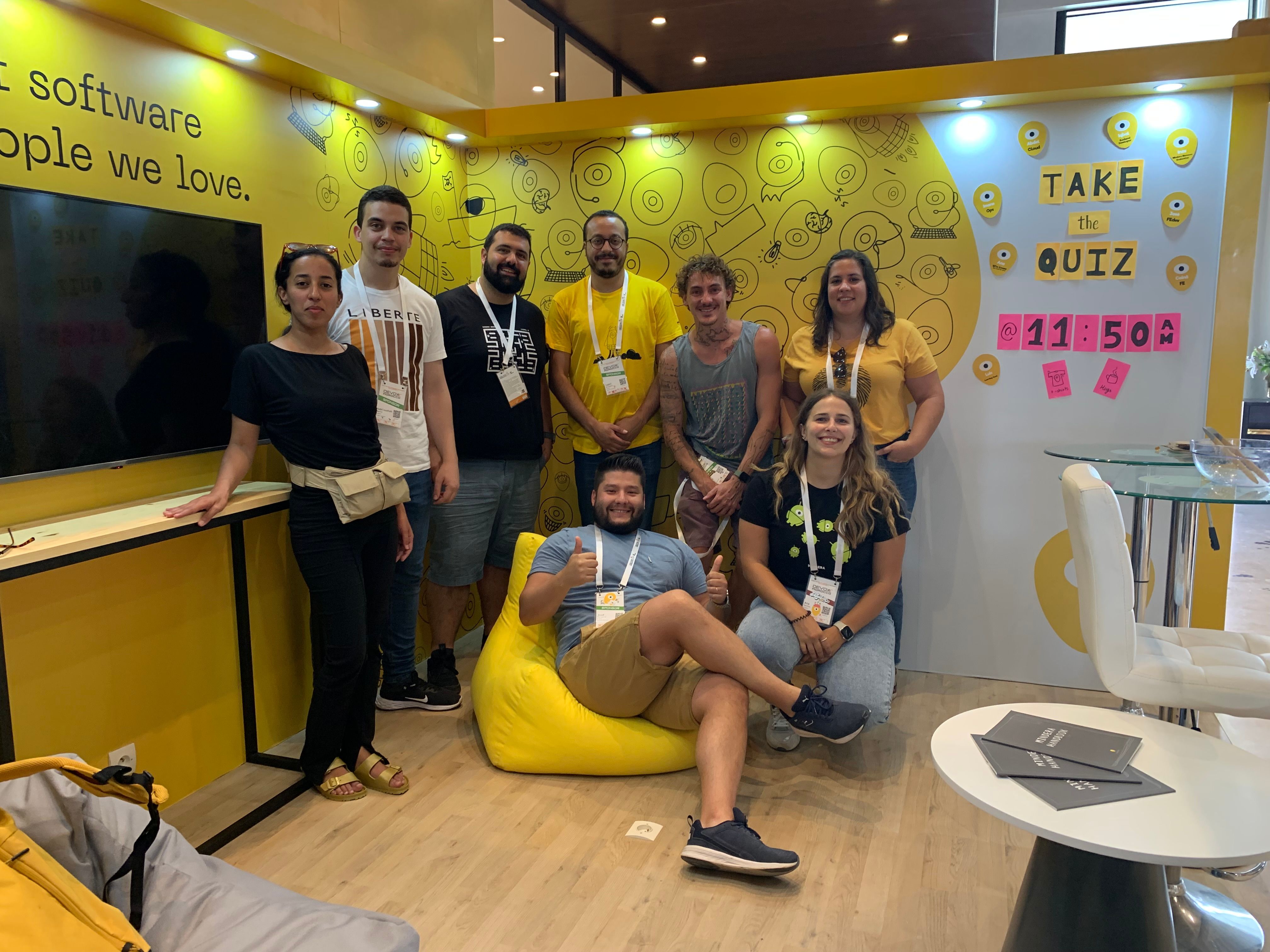 A group of Minders in our booth in Morocco Devoxx 2023, the booth features yellow Minders (our logo), a tv and our slogan