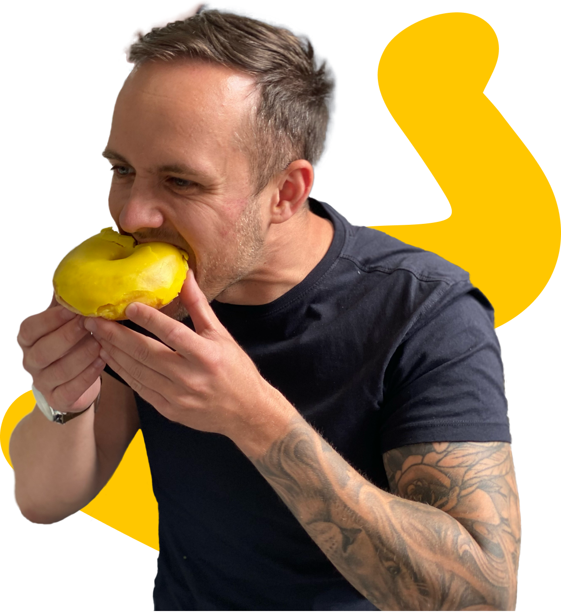 A male Minder, with tattoos on his left arm, a watch on his right wrist, and wearing a black t-shirt, eats a yellow doughnut that represents the main brand colour for software engineering company Mindera.