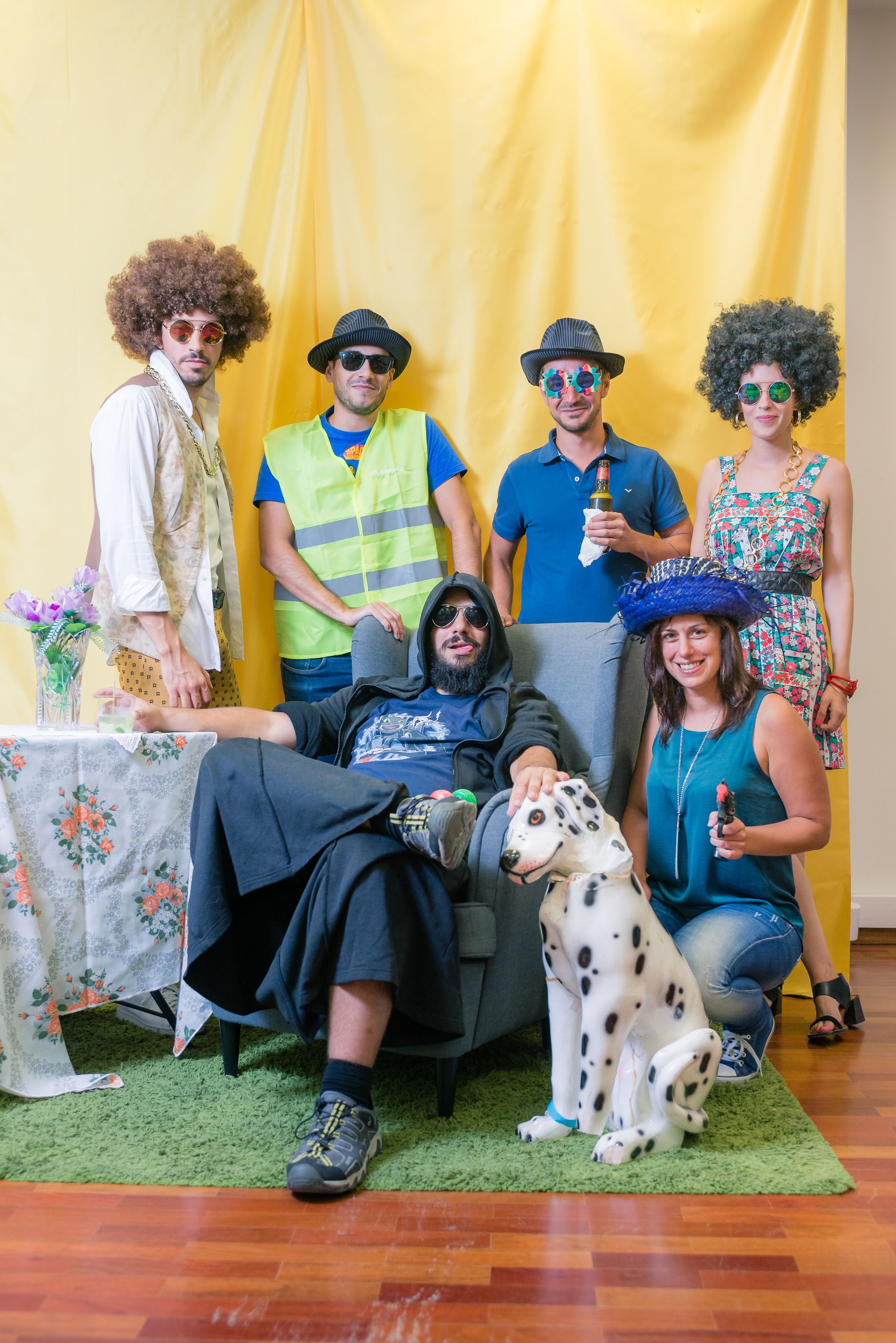 Five male Minders, two female Minders, and a life-size dalmatian toy dog posing for the camera. Six of the Minders are wearing sunglasses, three of the Minders are wearing hats, and two of the Minders are wearing afros. 