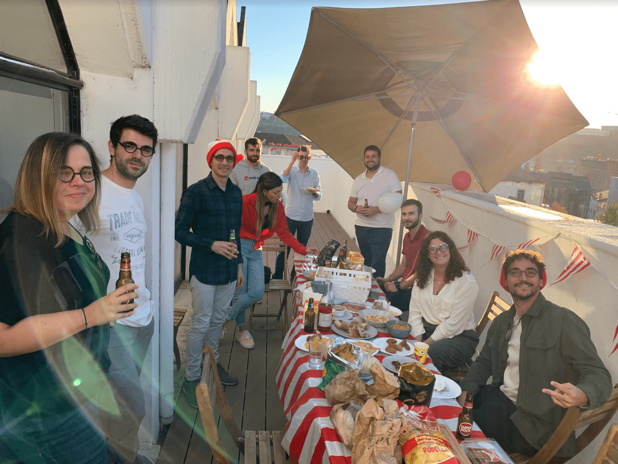 Ten Minders sat at on the balcony of the Coimbra office of Mindera, eating food, having drinks, and talking.