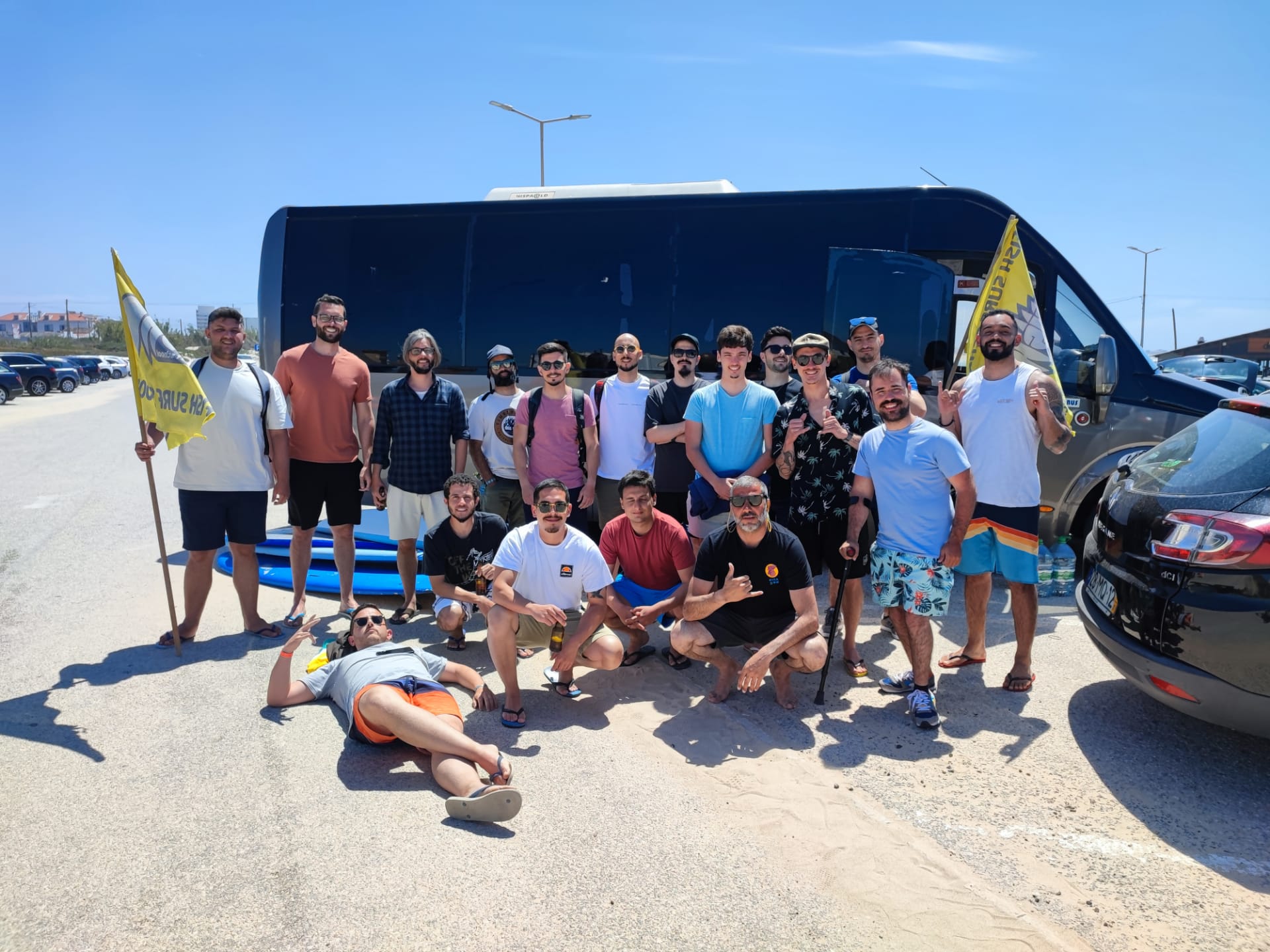 18 Minders in front of a mini bus on a hot day.