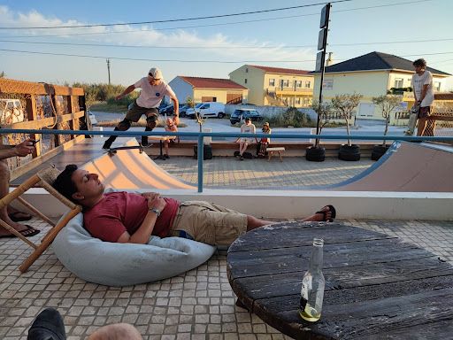 A Minder takes a nap on a beanbag chair, with people skateboarding in the background.