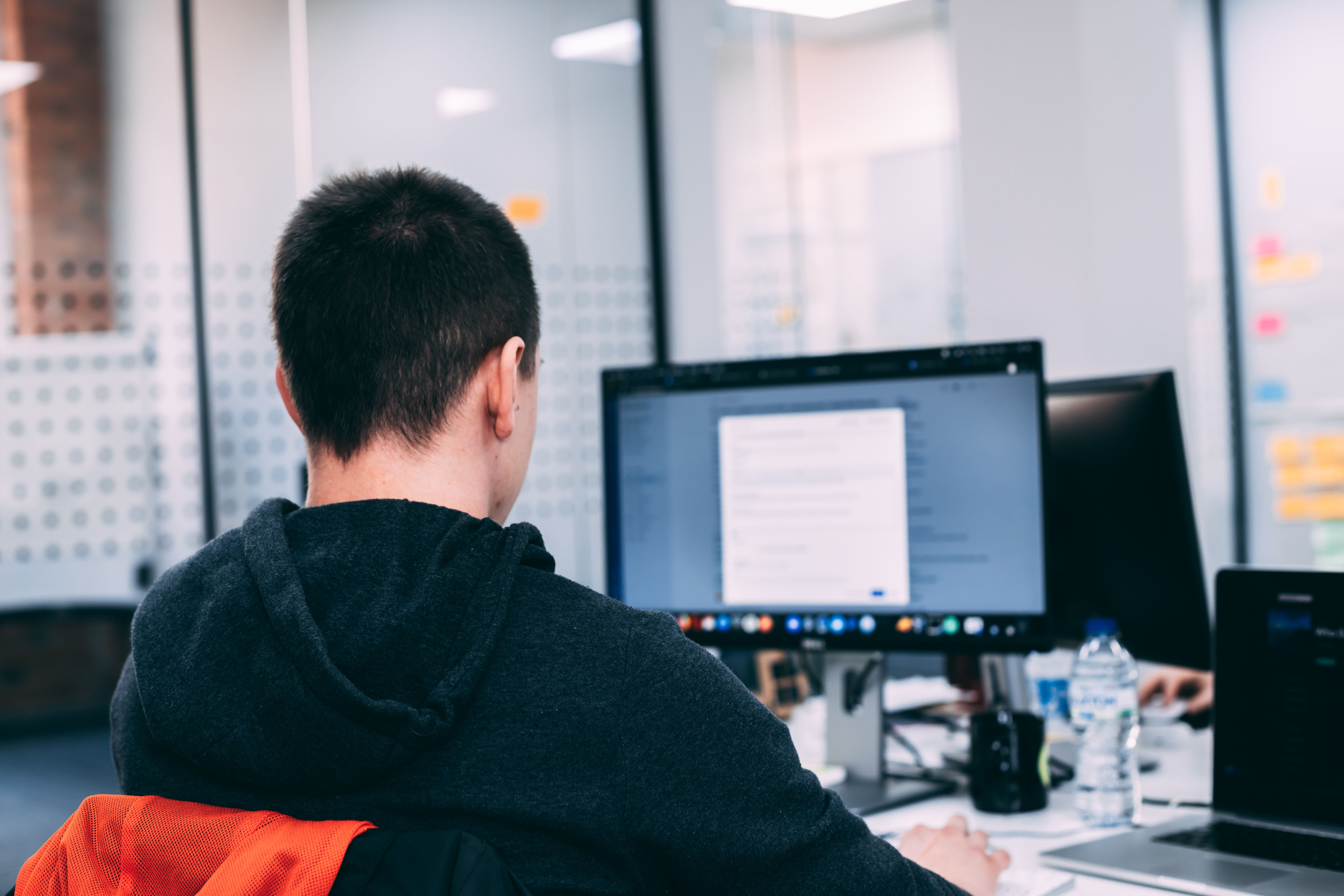 A person working at their computer, with their back to the camera.