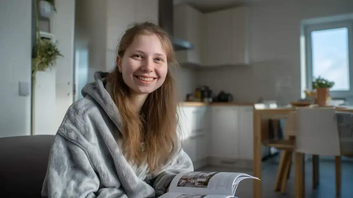 Mladá usměvavá žena v moderní kuchyni symbolizující nezávislé bydlení.