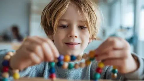 Malý chlapec s vývojovou dysfázií trénuje jemnou motoriku navlékáním korálků při ergoterapii.