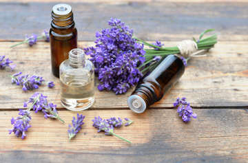 Bottles essential oil with one spilled wooden background bouquet lavender flowers