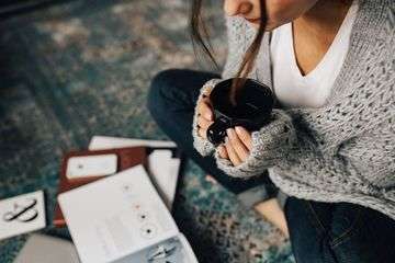 Kaboompics woman reading magazines on the floor while enjoying hercup of tea