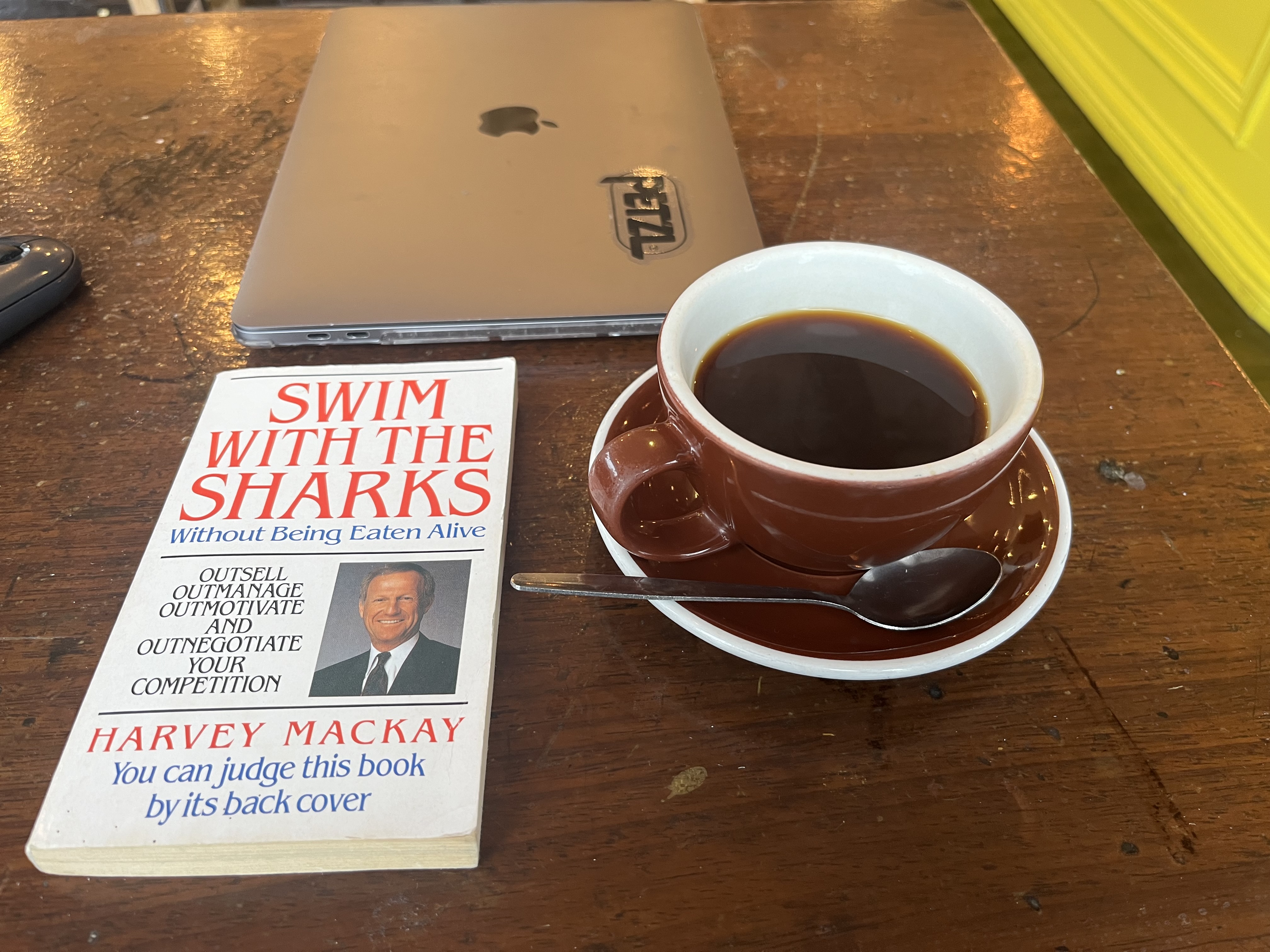 A book titled 'Swim With The Sharks' next to a cup of coffee
