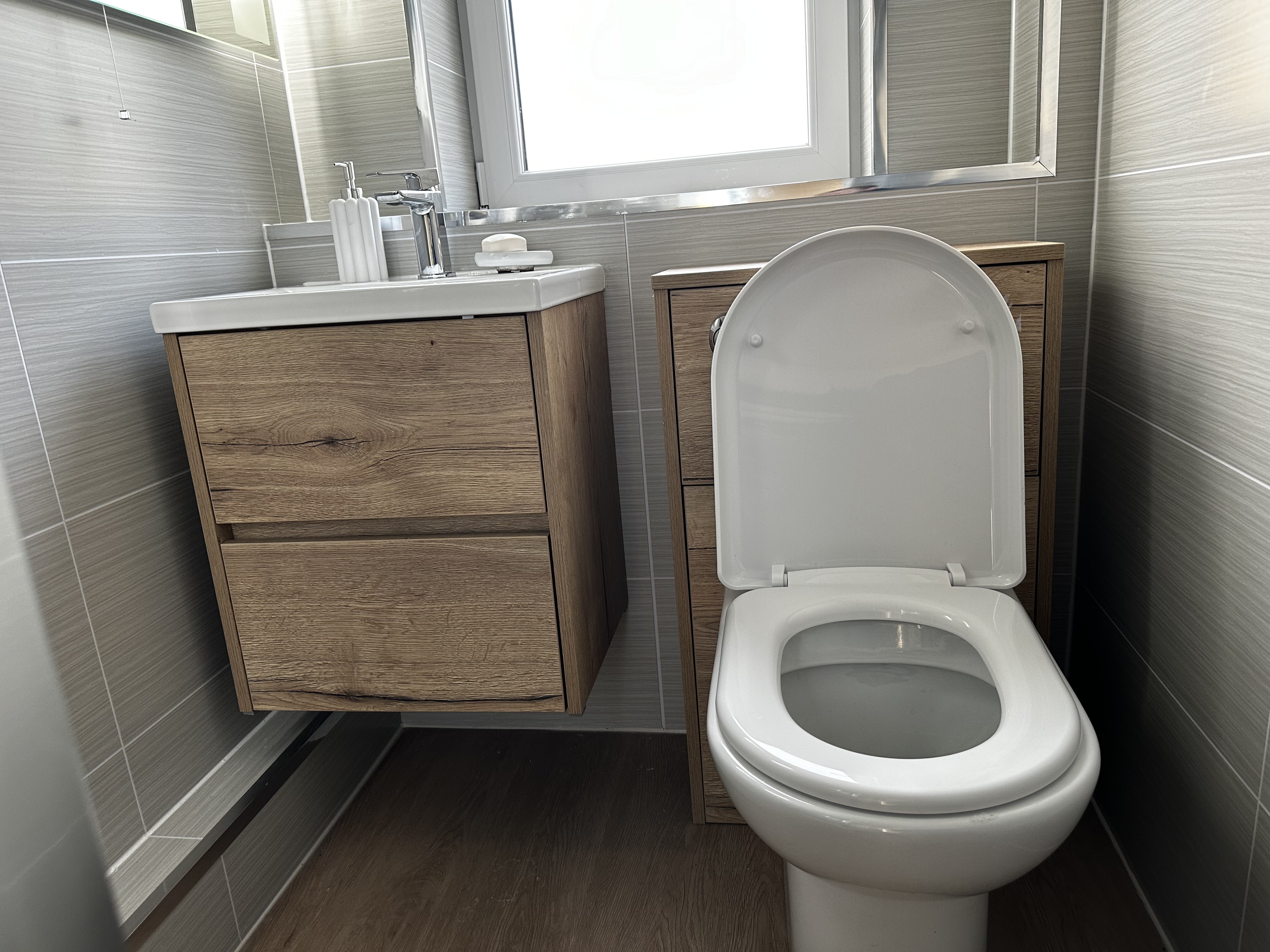 Floating oak vanity unit and toilet with natural light from the window.