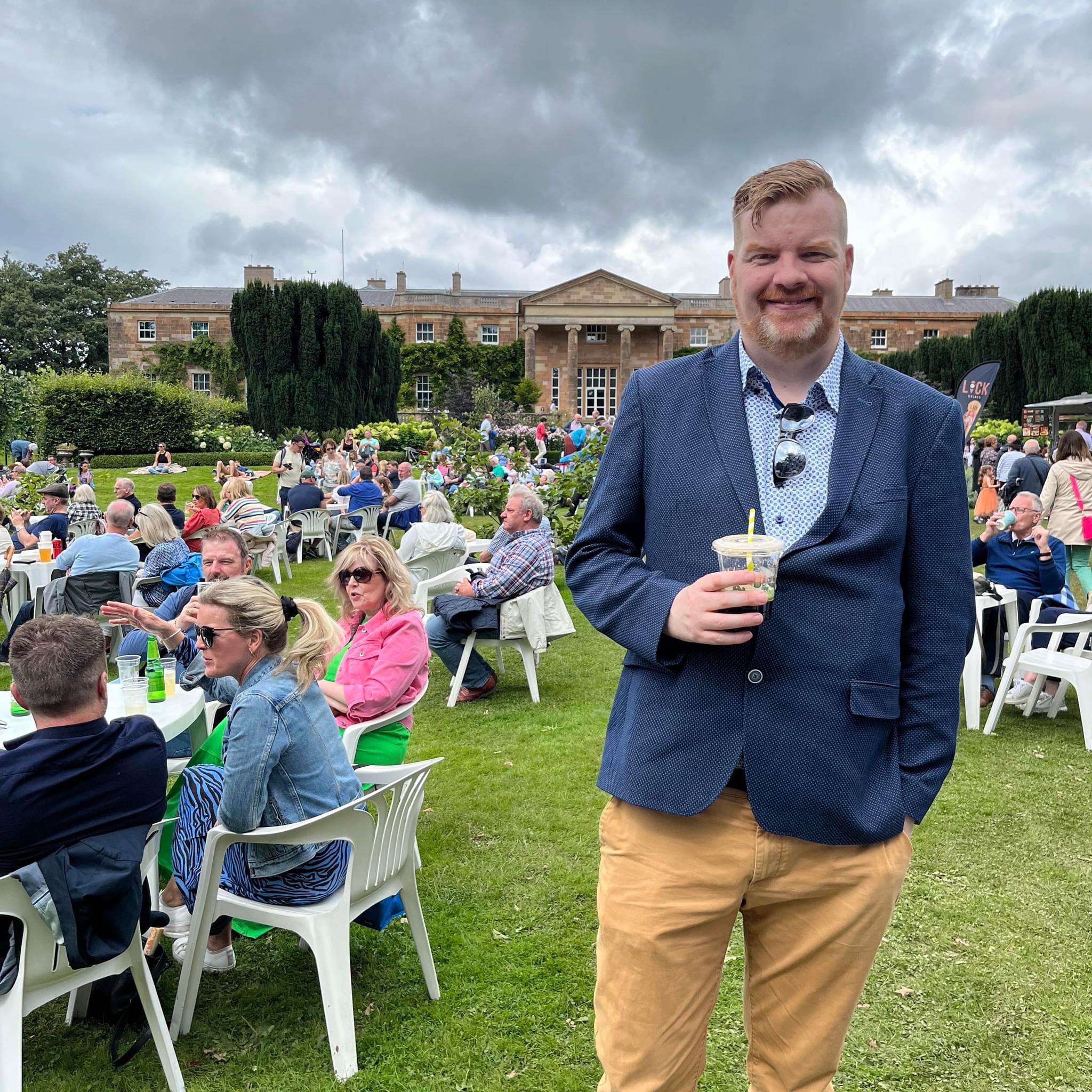 A man standing outdoors at an event with people in the background