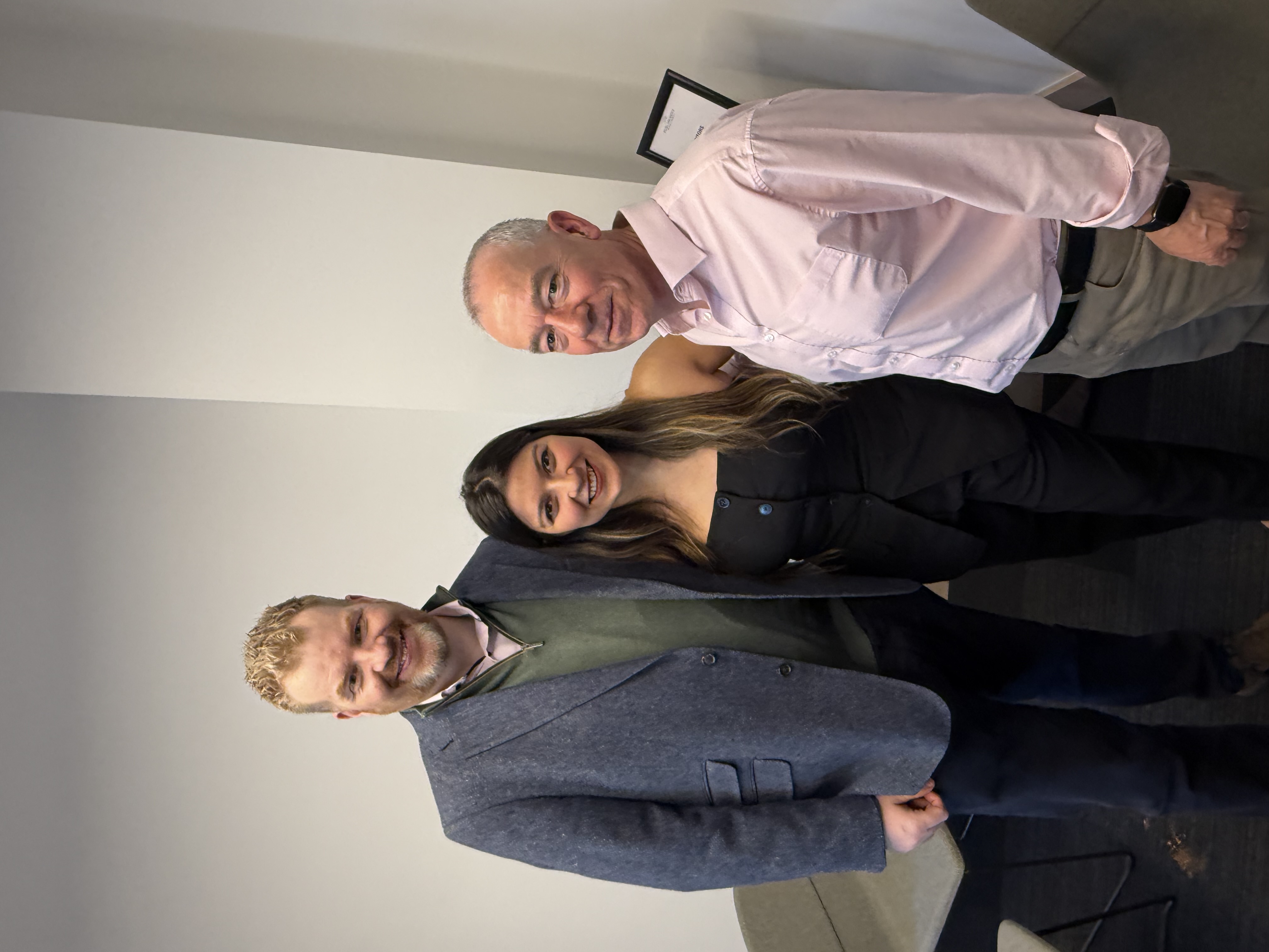 Three people smiling and posing for a photo at an event