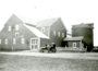 Man standing in front of possibly a Model-T in front of a barn, North                      Oaks Farm.