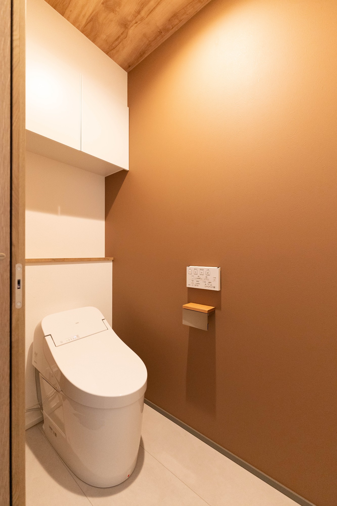 ２階のトイレは、シンプルな中により温かい印象になるよう、ブラウンと木目のアクセントクロスを採用