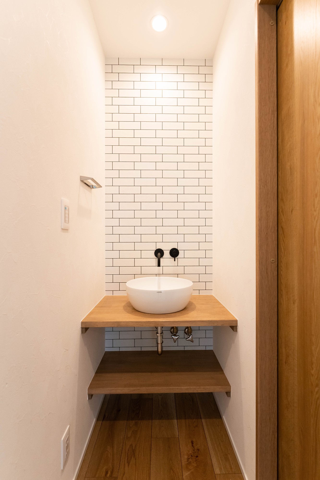 多目的に使用できる２階の独立洗面台は、白いタイル調のクロスとブラックの水栓の対比とした