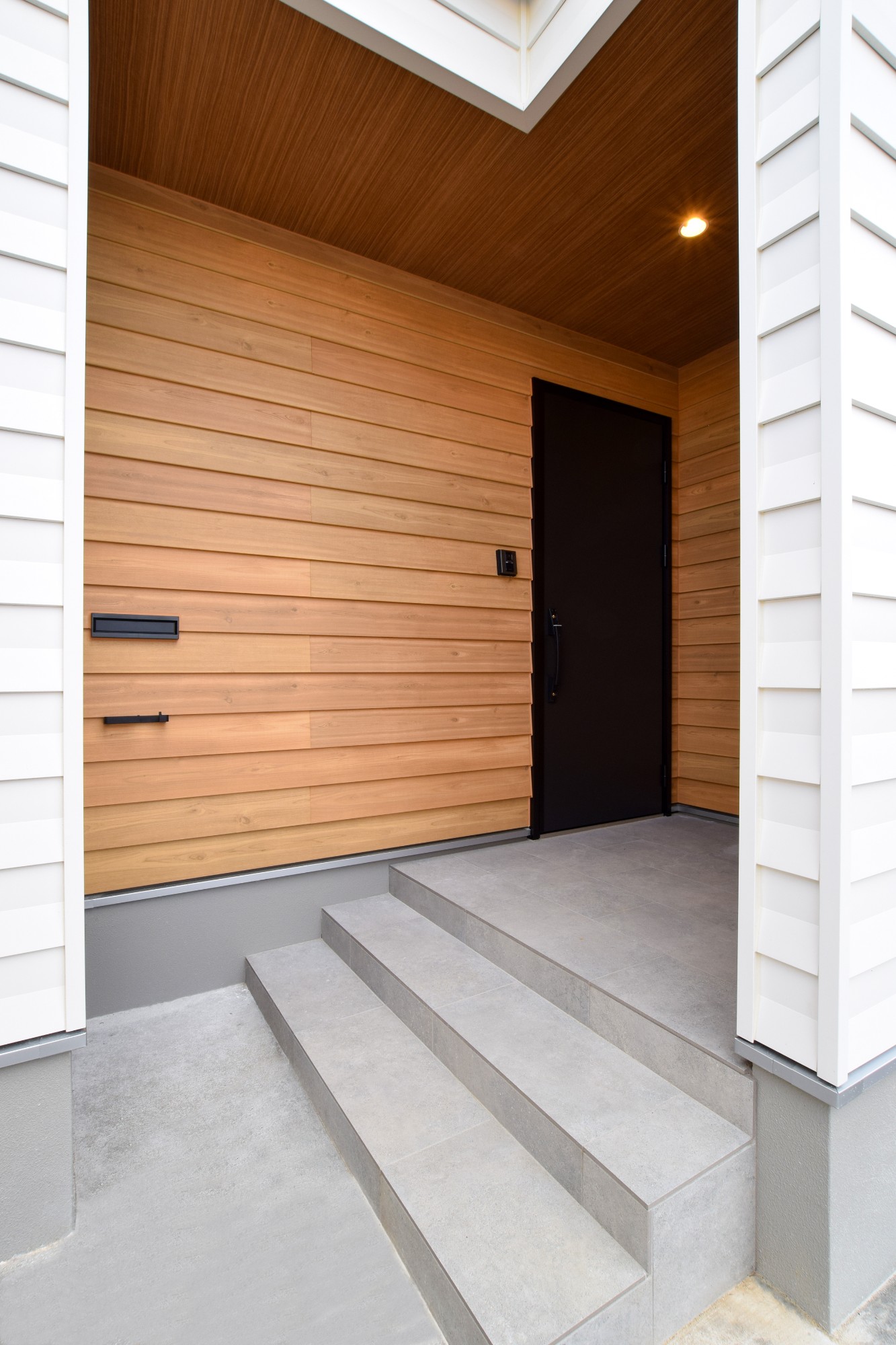 玄関ポーチ周りはラップサイディングの木目調のものを採用。より立体感がでて、木目の質感が強調されるような外壁材をセレクトした